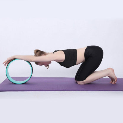 Yoga Pilates Circle Ring being used for a deep stretch on a purple mat by a woman in athletic wear.